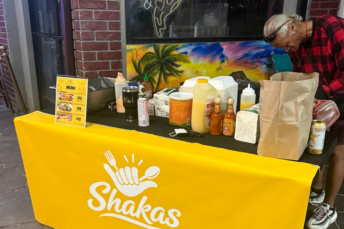 Shaka's branded yellow table, menu stand and food-service setup at an outdoor pop-up.